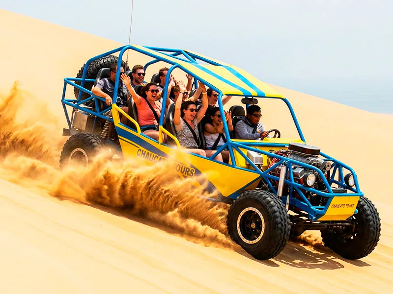 Tubular arenero gigante bajando una duna a toda velocidad en el desierto California de Paracas, turistas disfrutando la adrenalina con seguridad.