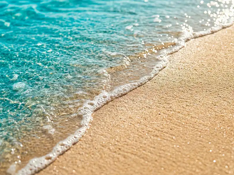 Primer plano de aguas turquesas y arena en las playas del tour reserva nacional paracas