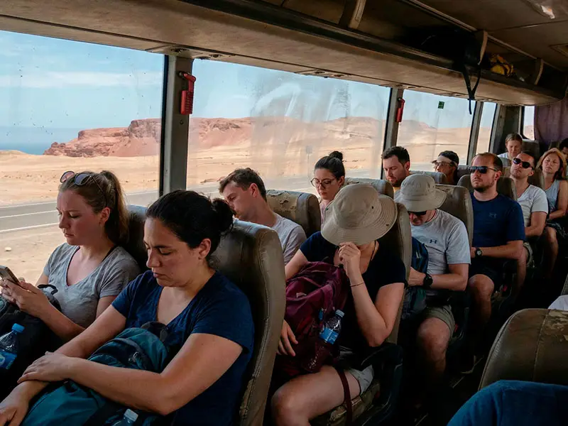 Vista desde el interior de un bus turístico lleno de gente mirando el paisaje de Paracas a través de una ventana.
