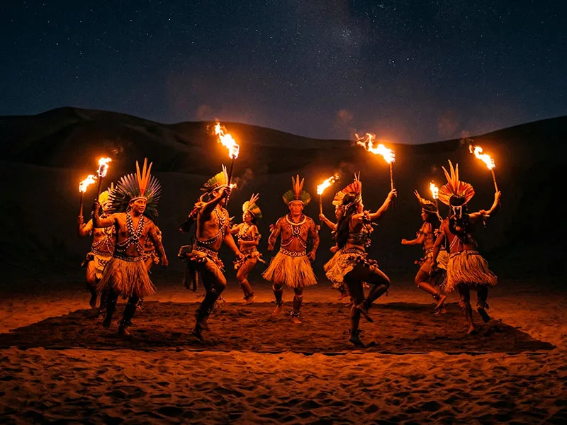 Show de danza de la selva con trajes tradicionales y antorchas en medio de las dunas nocturnas de Paracas.