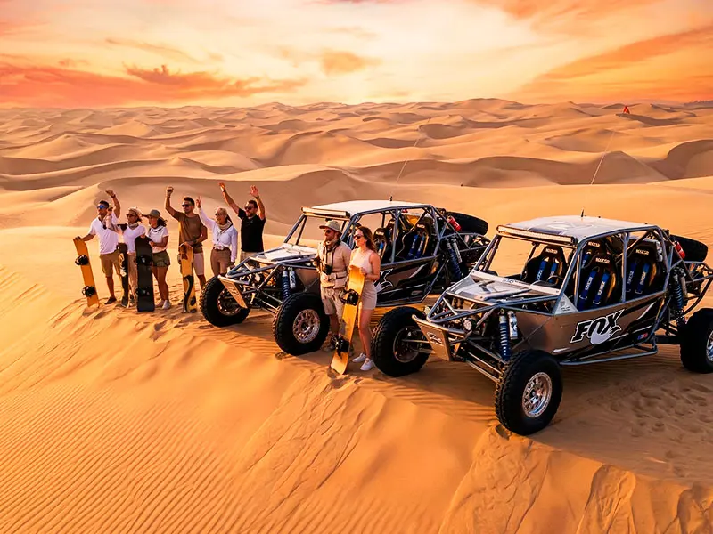 Dos vehículos tubulares de alta gama con un grupo de turistas VIP en la cima de una duna virgen en el desierto de California