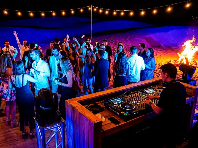 Fiesta nocturna privada con DJ profesional e iluminación robótica en tarima de baile en el desierto