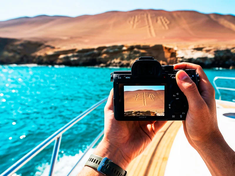 Turista capturando la foto perfecta del Candelabro desde un ángulo frontal exclusivo con Paracas Blue Tours.