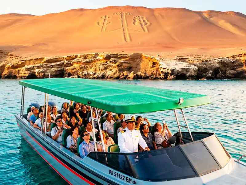 Pasajeros de la lancha privada El Mesías III admirando el Candelabro de Paracas guiados por un capitán oficial en un tour VIP exclusivo por Fiestas Patrias.