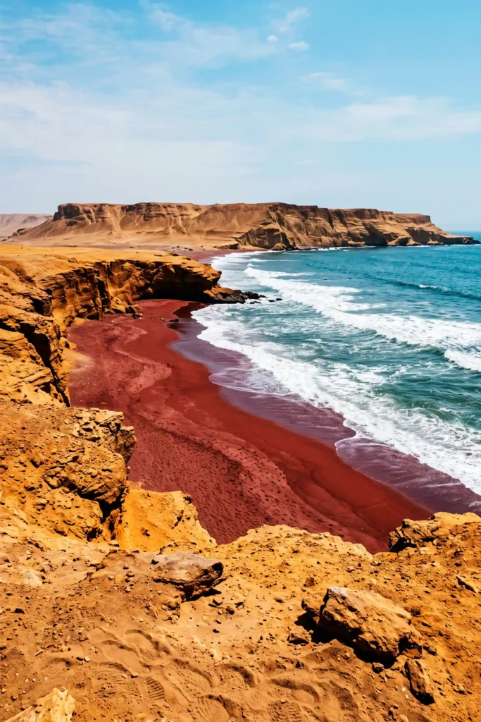 Vista cercana de Playa Roja desde el mirador de la Reserva Nacional de Paracas, con arena rojiza, acantilados y océano Pacífico